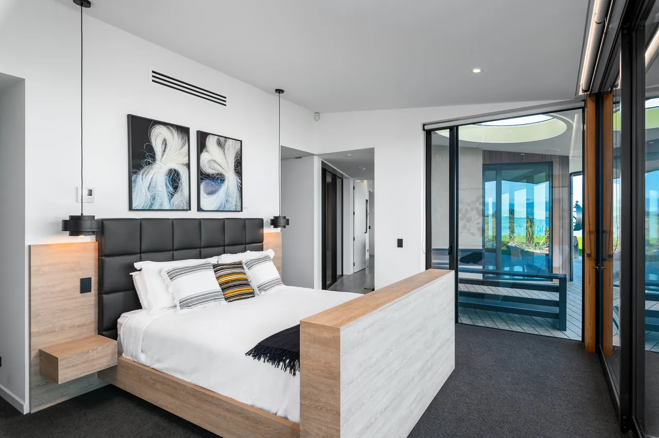 Bedroom with artwork, pendant lights and the ensuite beyond